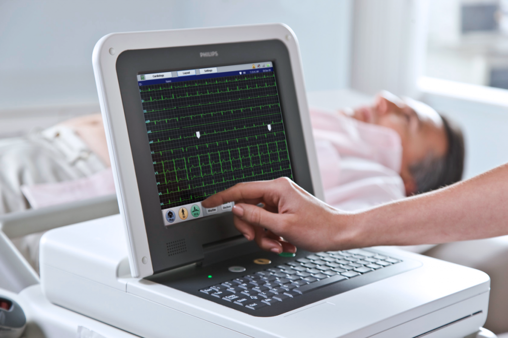 A patient's heart activity is being monitored using a medical device displaying an electrocardiogram.